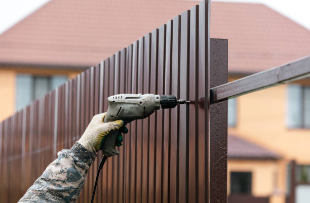 Workers install a metal profile fence. fence installation services in Hamilton